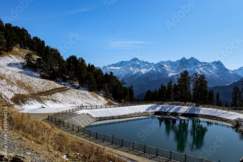 Snow-capped mountain peaks and lake, water. Arkhyz