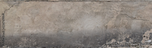 A gray plastered wall with a crumbling dirty texture