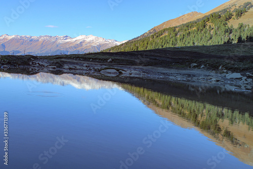 Snow-capped mountain peaks and lake, water. Arkhyz