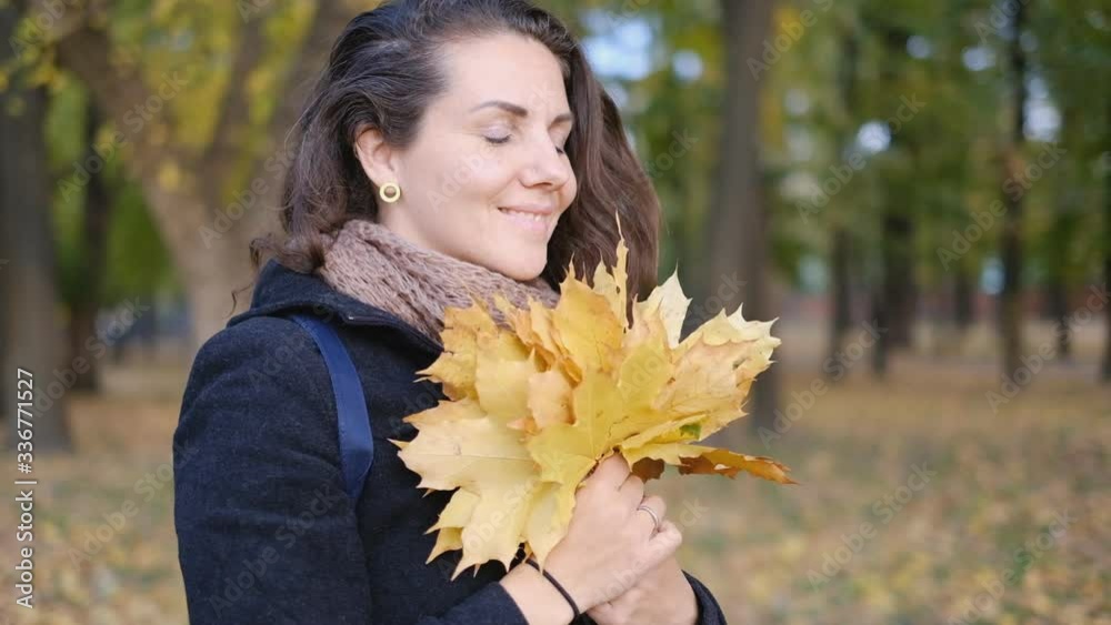 A young woman holds yellow autumn leaves in her hands. A young woman holds yellow autumn leaves in her hands.