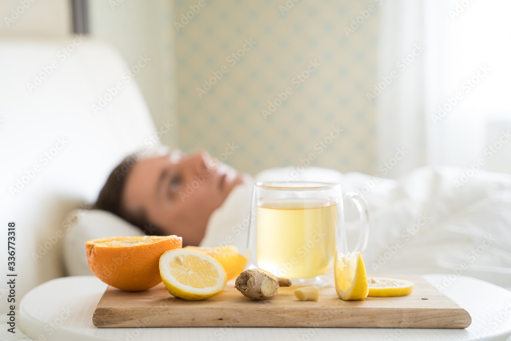 Cup with antipyretic drugs for colds,flu.Sick man in bed. Tea with citrus vitamin C,ginger root,lemon,orange.Wooden tray. Home self-treatment.Medical quarantine antiviral covid-19 coronavirus therapy Cup with antipyretic drugs for colds,flu.Sick man in bed. Tea with citrus vitamin C,ginger root,lemon,orange.Wooden tray. Home self-treatment.Medical quarantine antiviral covid-19 coronavirus therapy