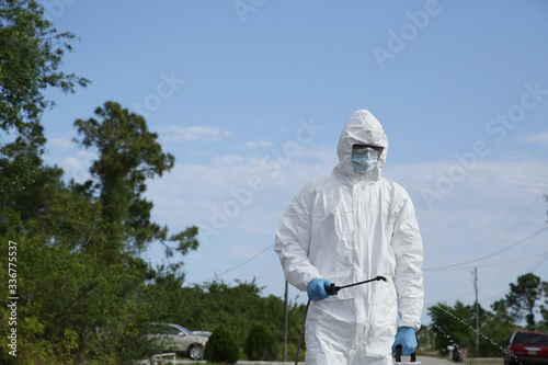 Covid-19 Coronavirus virus. A man in protective clothing in a white overalls disinfects and decontaminates in public places as a prevention against coronavirus disease 2019. Quarantine.