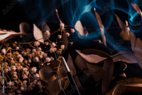 Stick holder and incense stick with leaves and flowers on black background