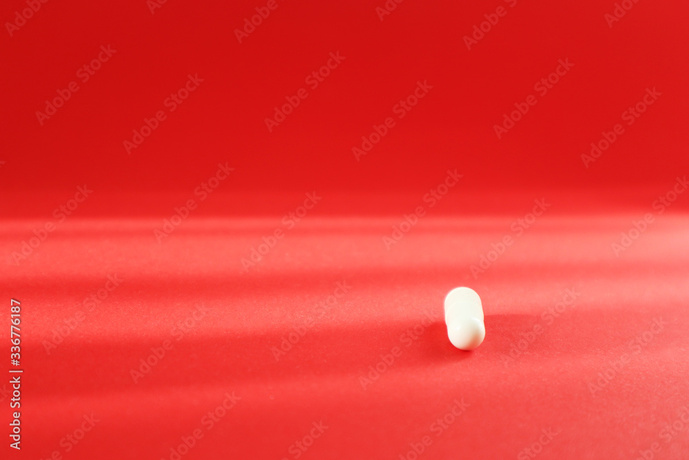 White pill on red background. Top view with copy space. Medicine concept. White pill on red background. Top view with copy space. Medicine concept.