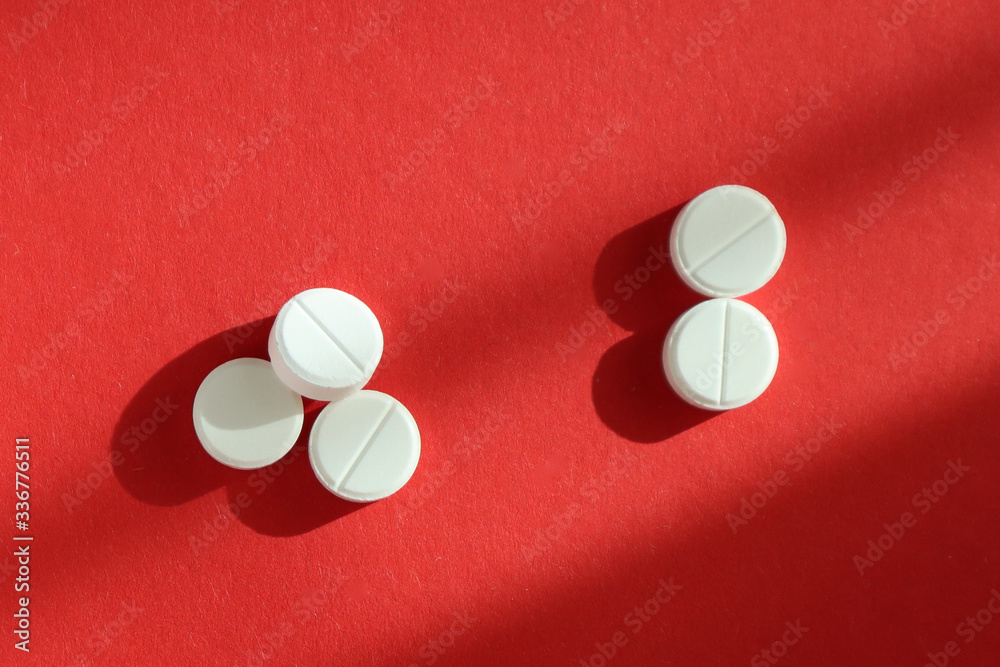 White pills on red background. Top view. Medicine concept. White pills on red background. Top view. Medicine concept.