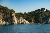 Beautiful rocky coast of a sea resort with rich green vegetation, view from the blue sea