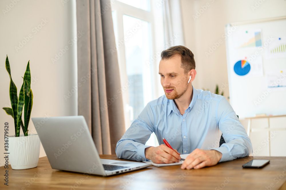 Guy in a formal shirt with airpods uses a laptop Guy in a formal shirt with airpods uses a laptop