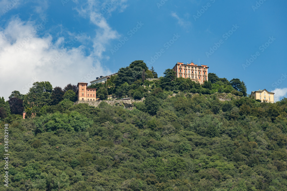 Como, ITALY - August 4, 2019: Apartments, villas, hotels on the green forested mountainsides near Lake Como. Beautiful Italian Como city. Warm sunny summer day in very popular holiday destination