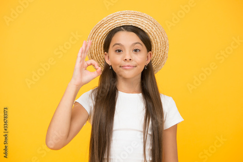 cheerful little girl wear straw hat. ready for beach party. small beauty. happy kid show ok gesture. she love summer vacation. spring fashion for kids. childhood happiness