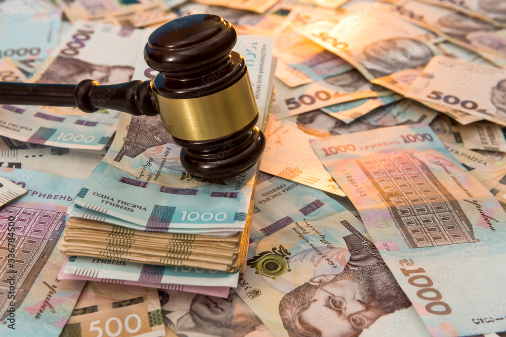 wooden hammer on ukraine money as background. 500 and 1000 new uah grivna
