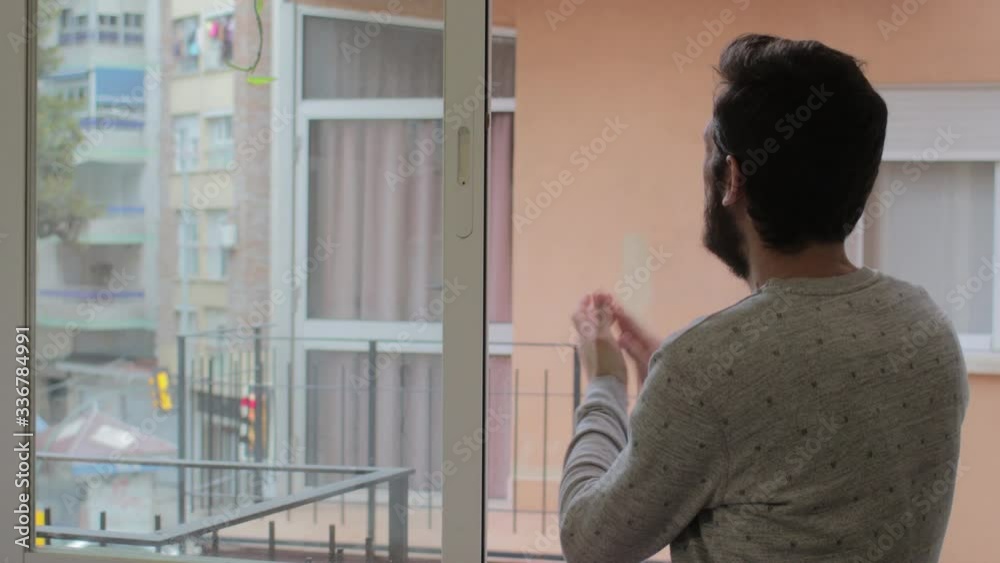 Man clapping on the balcony in support of the staff who fight the coronavirus Man clapping on the balcony in support of the staff who fight the coronavirus
