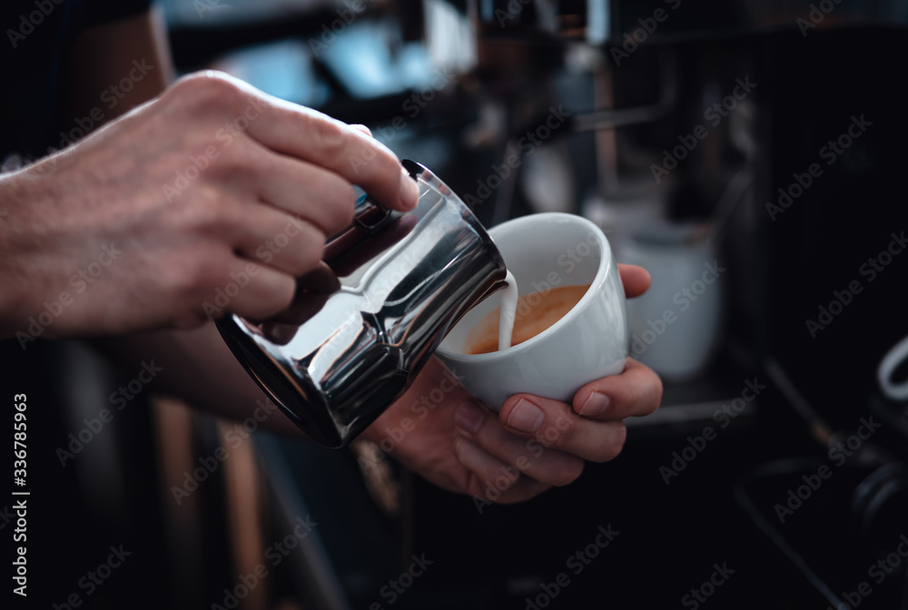 Close up of barista hands preparing cappuccino in cafe shop.