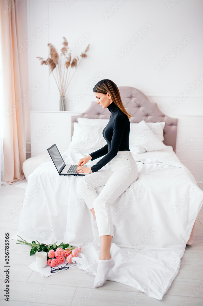 beautiful woman of European appearance works at a computer in a bright room at home, online work beautiful woman of European appearance works at a computer in a bright room at home, online work