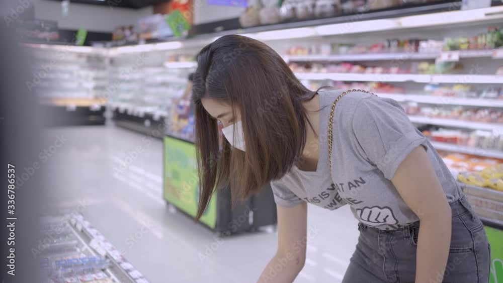 Young Asian woman in medical mask goes shopping at supermarket, stocking up on foods, lifestyle during covid19 corona virus pandemic crisis, healthy choice good selection, world pandemic, top shelf Young Asian woman in medical mask goes shopping at supermarket, stocking up on foods, lifestyle during covid19 corona virus pandemic crisis, healthy choice good selection, world pandemic, top shelf