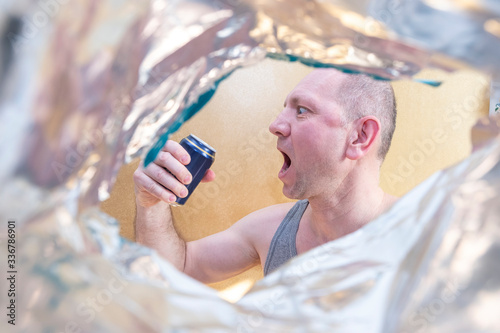 A man in a T-shirt is drinking a drink, beer, juice from a can. A man with a very open mouth. Emotions on the face. Light background. beer festival oktobrfest. photo