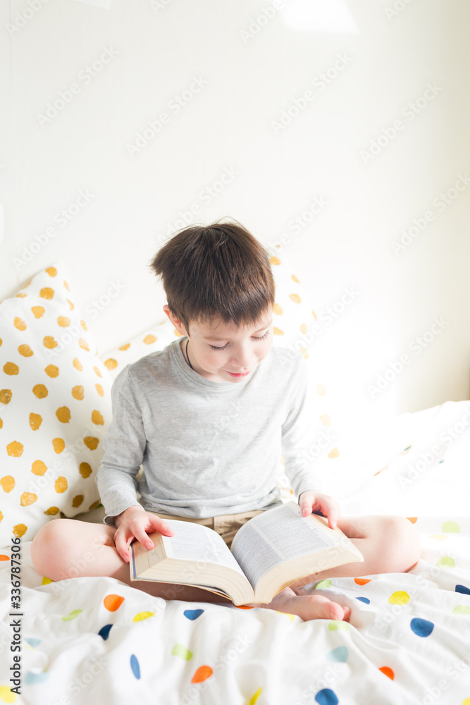 School Boy on bed and doing school homework reading book at home. Distance learning online education. Quarantine. Concept staying at home during emergency School Boy on bed and doing school homework reading book at home. Distance learning online education. Quarantine. Concept staying at home during emergency