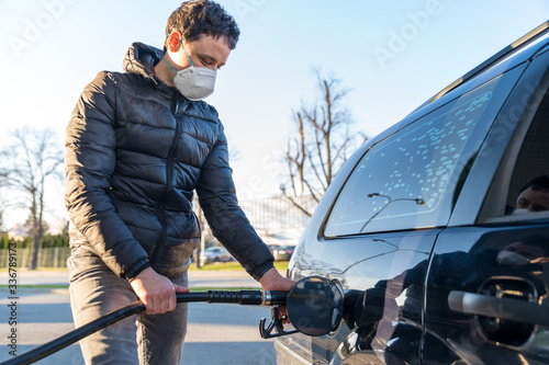 fueling the car at the time of the epidemic coronavirus with a respirator over his mouth and nose