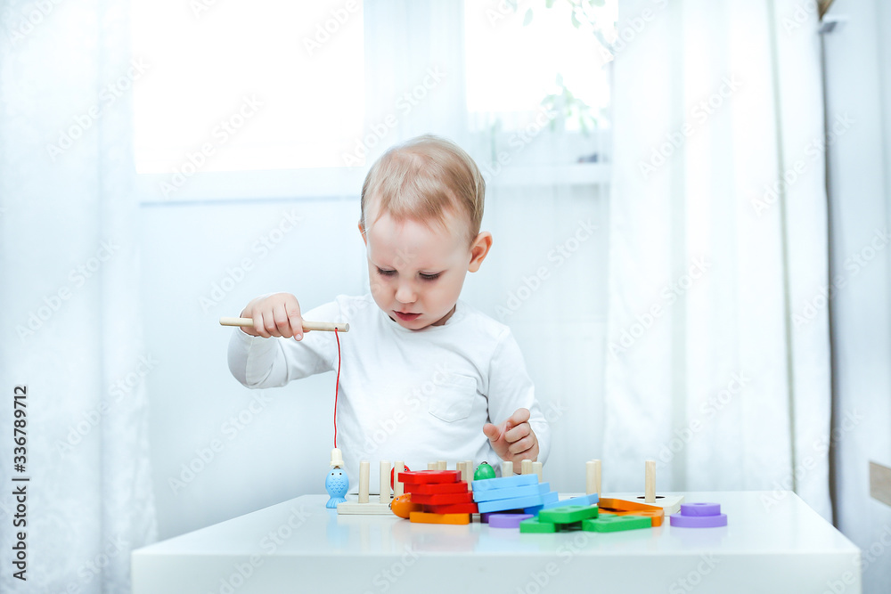 baby boy plays with educational toy. toddler play with a wooden toys at home. Toddler play with a color educational toy. Child play at the table in the baby room. Child development. baby boy plays with educational toy. toddler play with a wooden toys at home. Toddler play with a color educational toy. Child play at the table in the baby room. Child development.