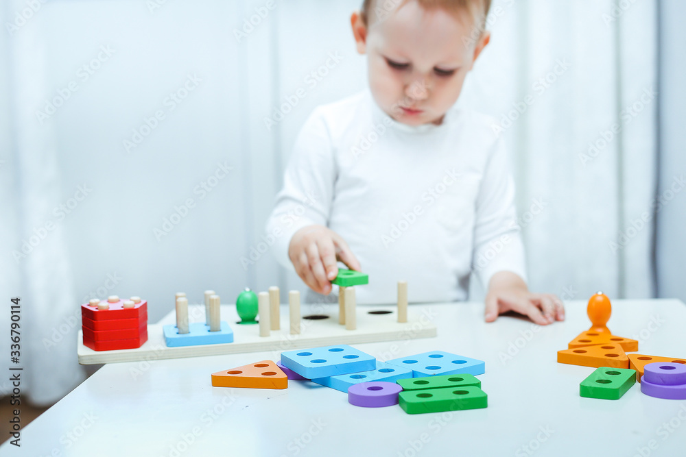 baby boy plays with educational toy. toddler play with a wooden toys at home. Toddler play with a color educational toy. Child play at the table in the baby room. Child development. baby boy plays with educational toy. toddler play with a wooden toys at home. Toddler play with a color educational toy. Child play at the table in the baby room. Child development.