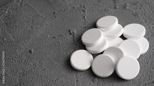 Bunch of white pills on gray background. Pile of the white tablets.