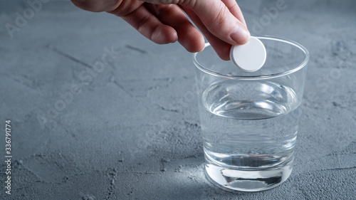 An effervescent aspirin tablet is thrown into a glass of water. Background with space for text. photo
