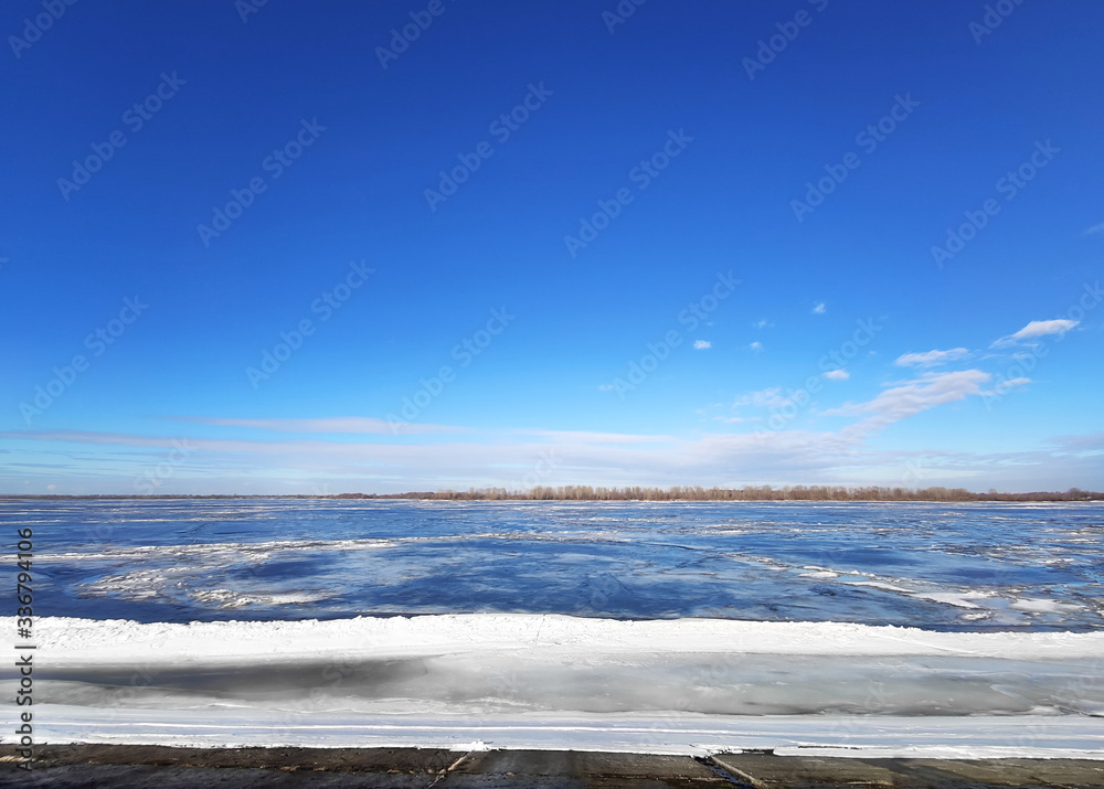 Beautiful early spring landscape. White clouds over the river and trees on on a sunny day after melting snow. Beautiful early spring landscape. White clouds over the river and trees on on a sunny day after melting snow.
