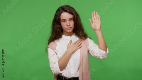 I swear! Responsible sincere brunette girl in white shirt making promise gesture with hand on heart, honest teenager taking oath, pledging allegiance. indoor studio shot isolated on green background