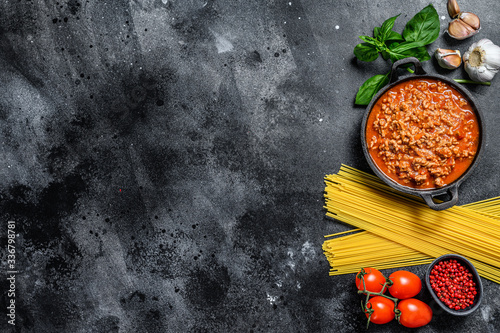 Italian food ingredients for Spaghetti Bolognese. Raw pasta, Basil, ground beef, tomatoes. Black background. Top view. Copy space