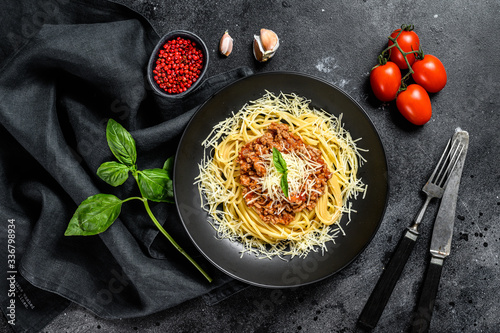 Spaghetti bolognese pasta with tomato and minced meat, parmesan cheese and basil. Black background. Top view
