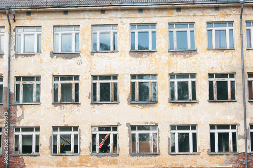 Decorative background - wall, windows. The photo shows the orange wall of the old school and many windows, in one of which a toy airplane is visible in red
