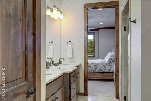 Classic simple small bathroom interior detailes with rich dark wood closet door and open door to the bedroom.