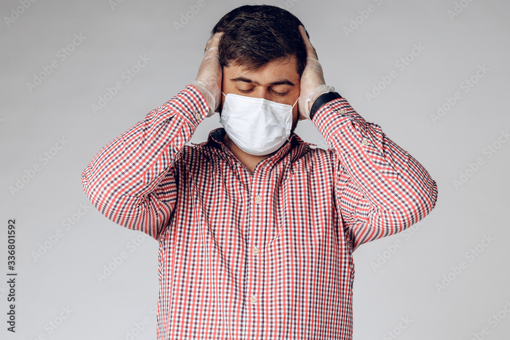Sick man in medical mask on face and protective gloves on hands feeling headache. Close up. Sick man in medical mask on face and protective gloves on hands feeling headache. Close up.