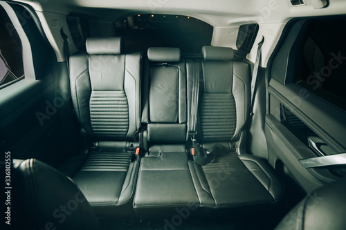 Dark luxury new car Interior. Back passenger seats in modern car. Leather backseats and seatbelts. Green matte tone