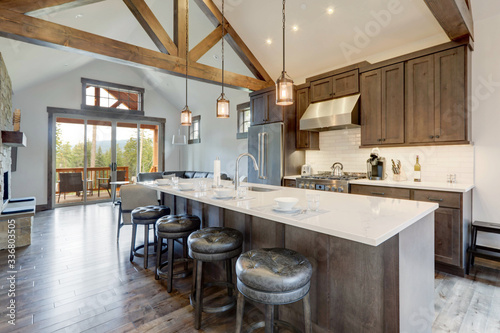 Amazing modern and rustic luxury kitchen with vaulted ceiling and wooden beams  long island with white quarts countertop.