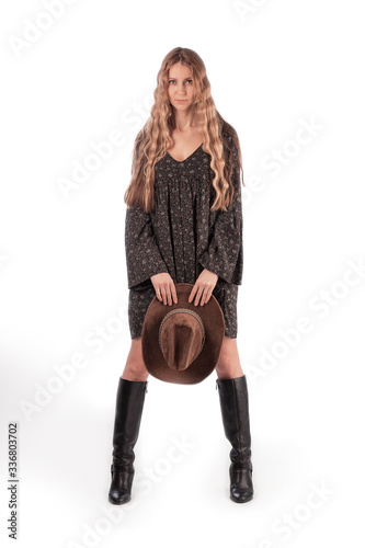 Girl with long blond hair with a cowboy hat in her hands, full length portrait. Isolate on a white background.