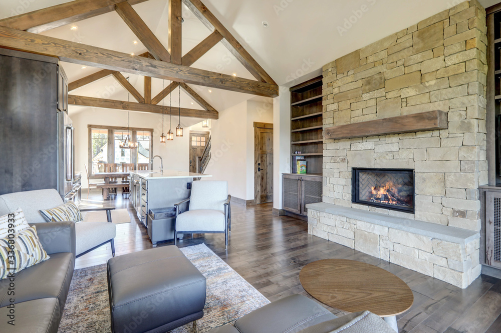 Beautiful large bright vaulted ceiling with large wooden beams and white walls living room interior with stone and leather sofa and dark grey hardwood. - obrazy, fototapety, plakaty 