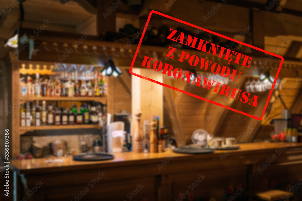 Defocused, blurred view of interior of traditional bar or restaurant, empty and closed due to covid 19 with Polish notice Closed due to Coronavirus