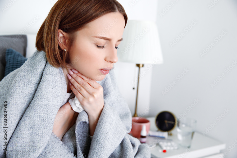 Sick woman covered in blanket at home in isolation at quarantine