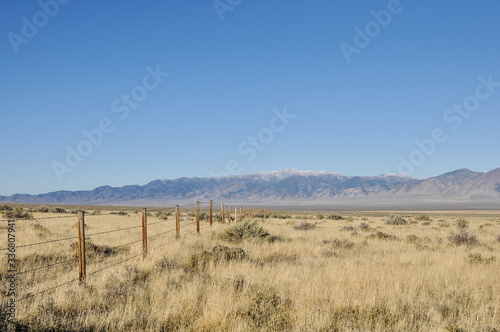 Fence running through grassland towards the mountains on the horizon