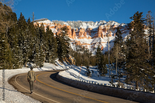 Man walking along roadway in Utah desert in winter.