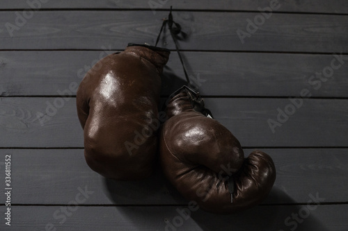 old boxing gloves made of brown genuine leather on a gray wall background © TetianaRUD