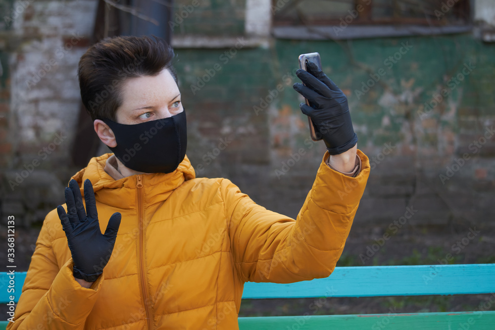 Middle aged european woman in protective black mask and gloves takes selfie on smartphone outside during coronavirus COVID-19 Epidemic Middle aged european woman in protective black mask and gloves takes selfie on smartphone outside during coronavirus COVID-19 Epidemic