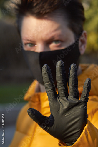 Middle aged european woman in protective black mask makes an warning gesture during coronavirus COVID-19 Epidemic. Sick woman wearing protection during pandemic. photo