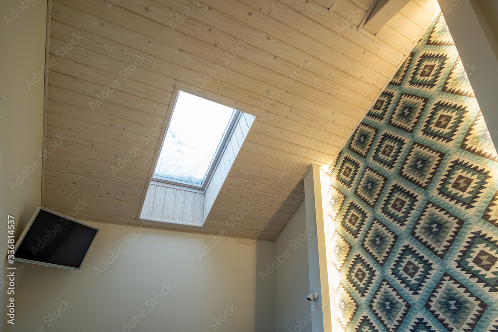 Wooden ceiling in a contemporary mansard room with attic window of ...