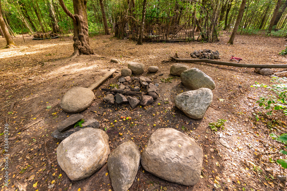 A campsite in the woods, with stone chairs and a fireplace green trees and a path through the forest. A campsite in the woods, with stone chairs and a fireplace green trees and a path through the forest.