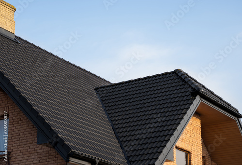 Brown metal tile roof. Roof metal sheets. Modern types of roofing materials. Roof of the house, metal roof tile against the blue sky. Building.