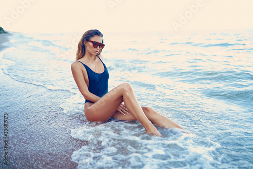 portrait of beautiful sexy caucasian sunbathed woman in leopard print sunglasses with long hair in swimsuit lying on summer beach.
