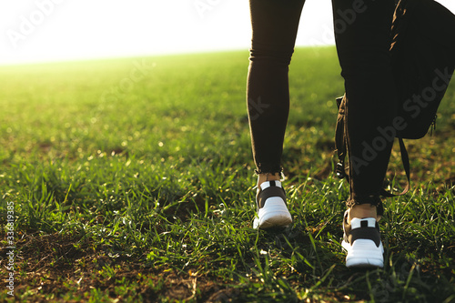 Legs of a girl wearing sports shoes and walking on the green grass.Sport, adventure, travel, explore, concept.