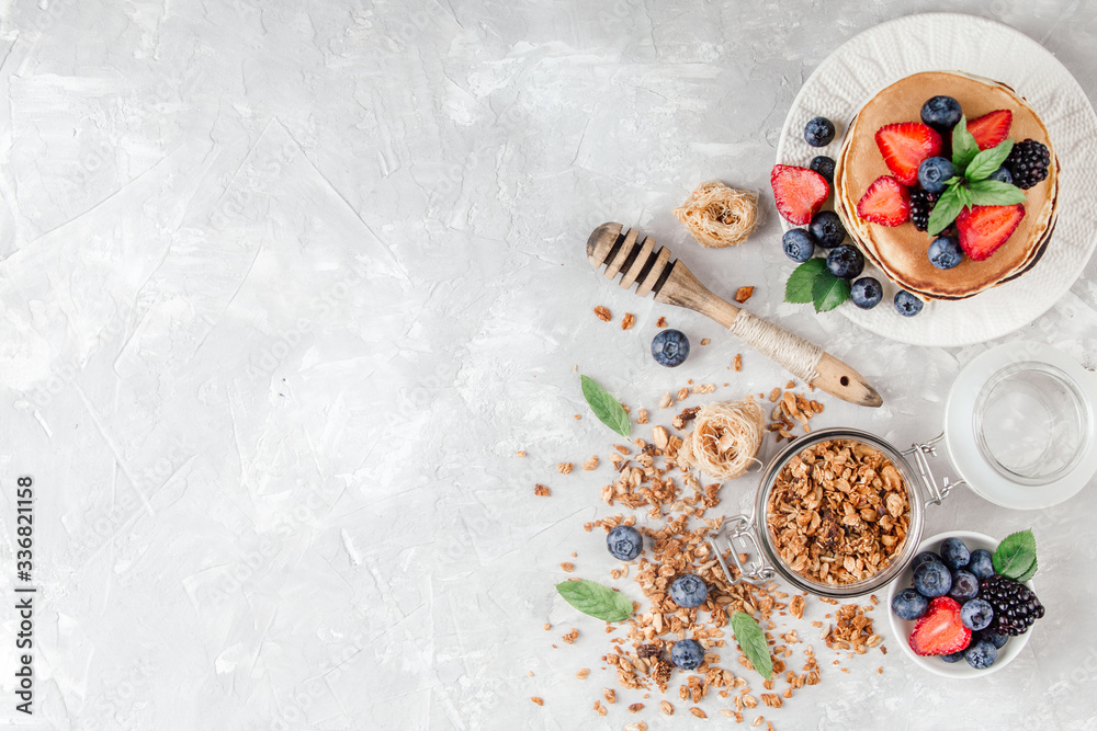 Healthy breakfast with american pancake, granola, fruits, berries on white background.
