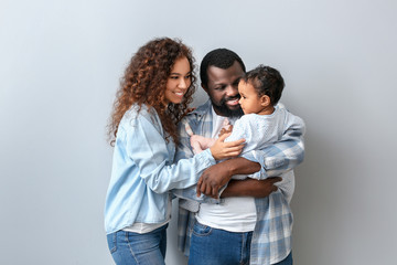 Happy African-American parents with cute baby on white background